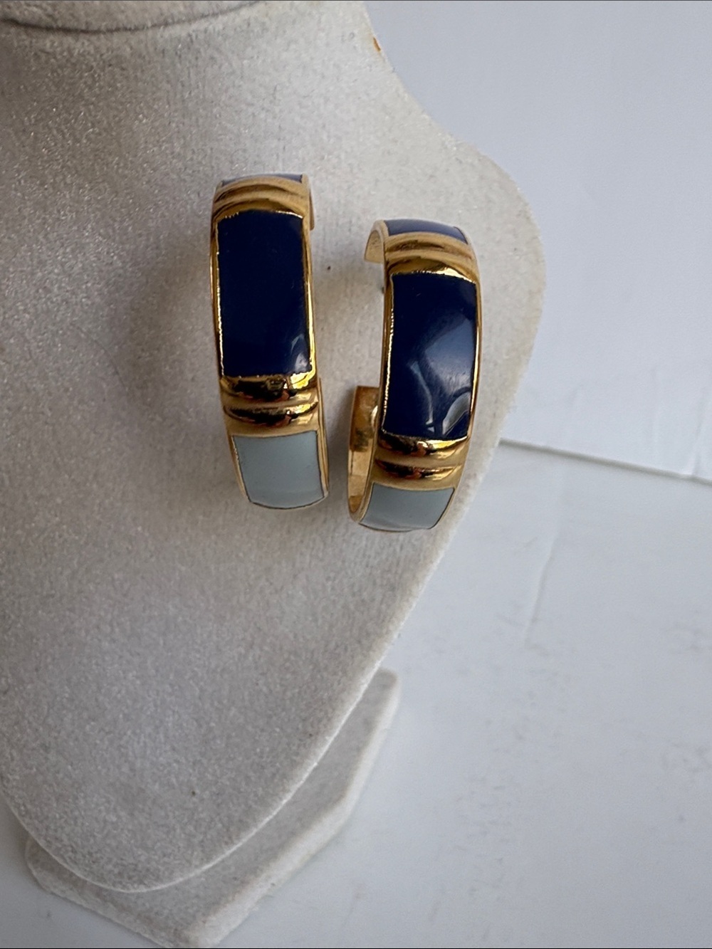 Gold toned hoop earrings featuring multi colored blue inlay vertical blue bands